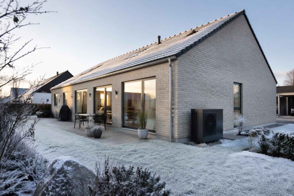 Vinterklar bolig i Danmark med varmepumpe, der holder stabil indetemperatur på en kold frostmorgen.